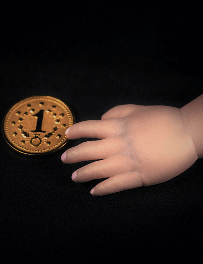 Hand reaching towards a gold coin with the number '1' on a black background
